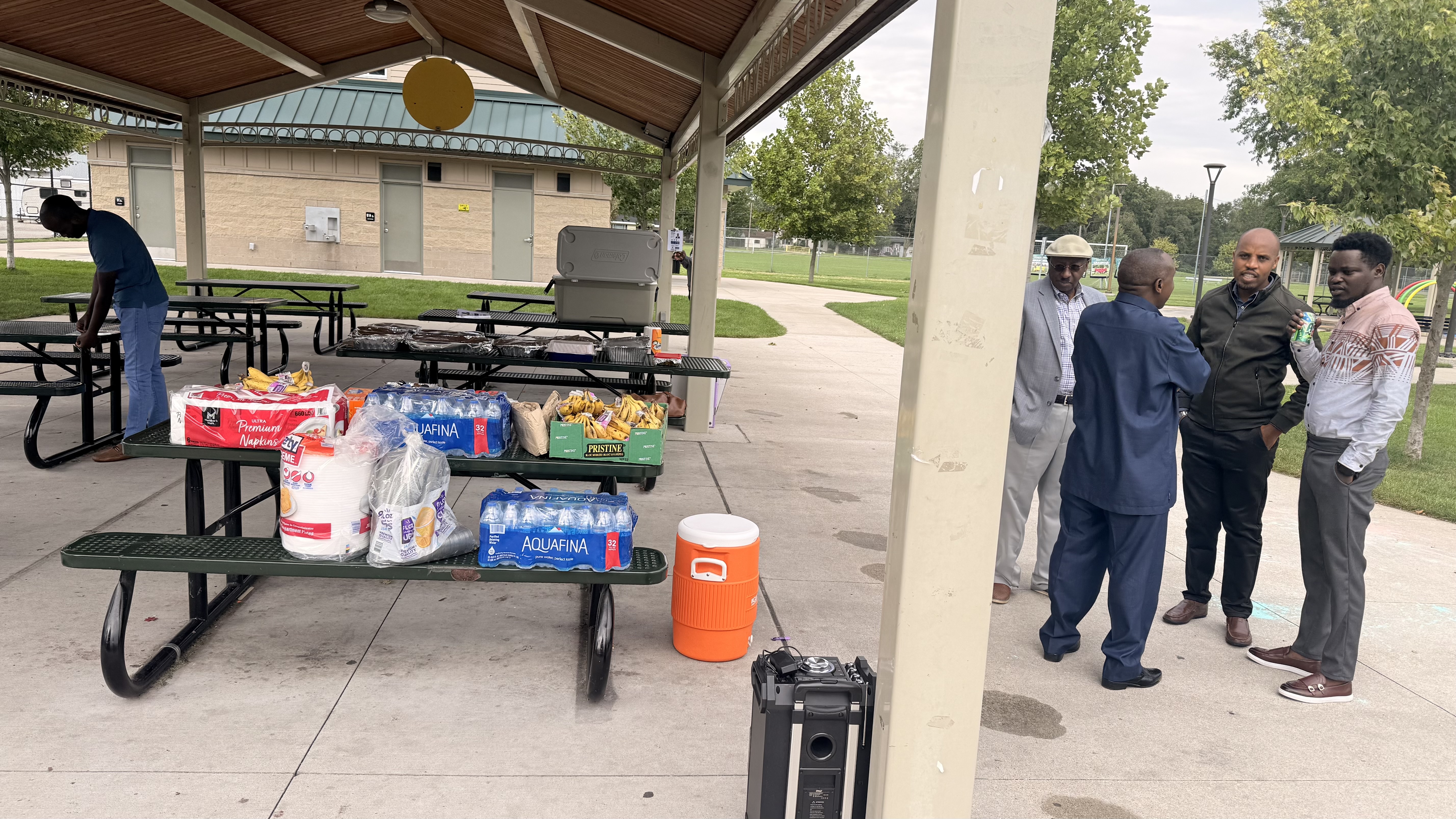 Community members prepare food and connect under the outdoor pavilion at Iwacu Rwanda Family Day.