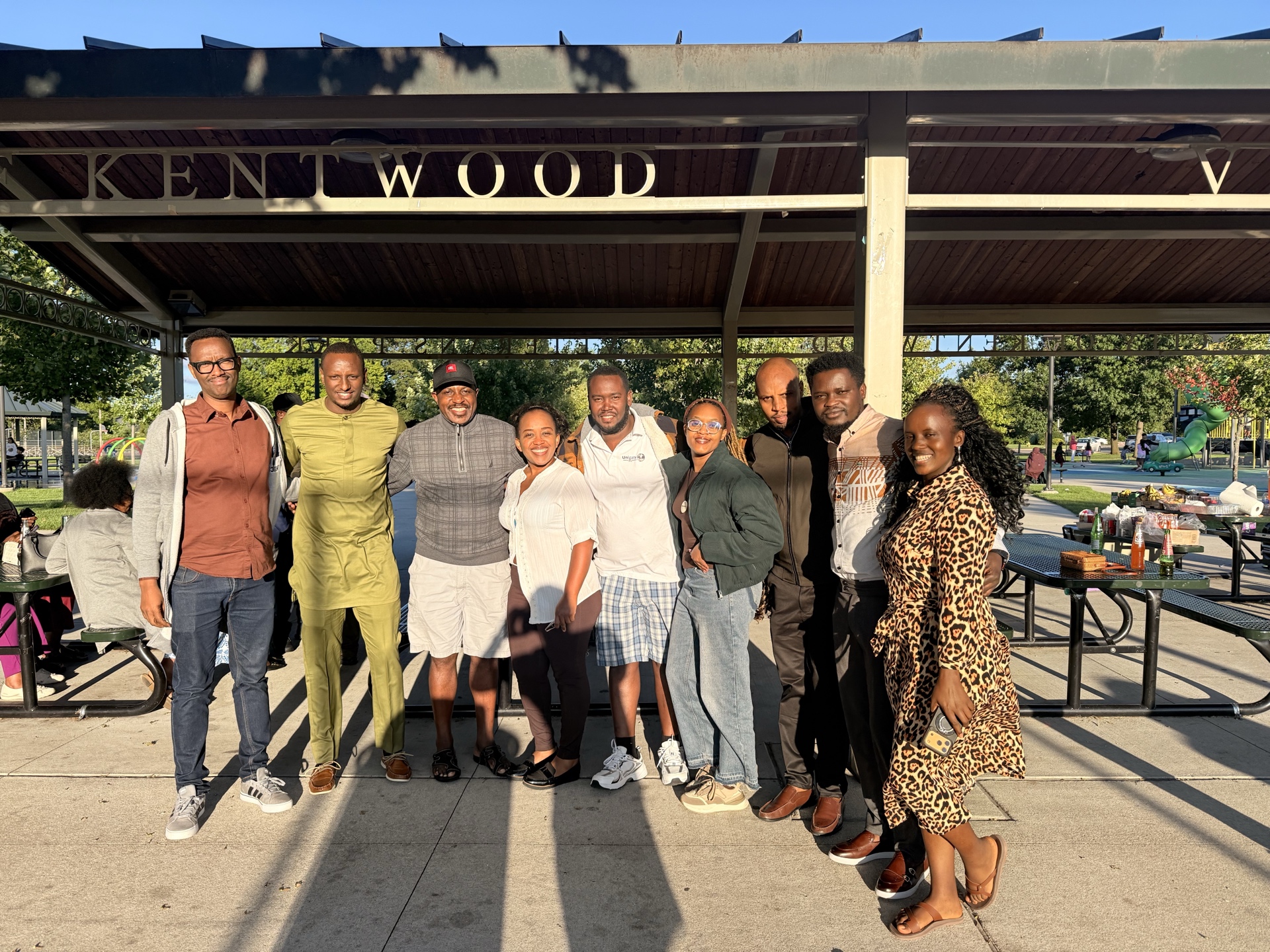 A larger group of Michigan Rwandan community members poses at the event pavilion.