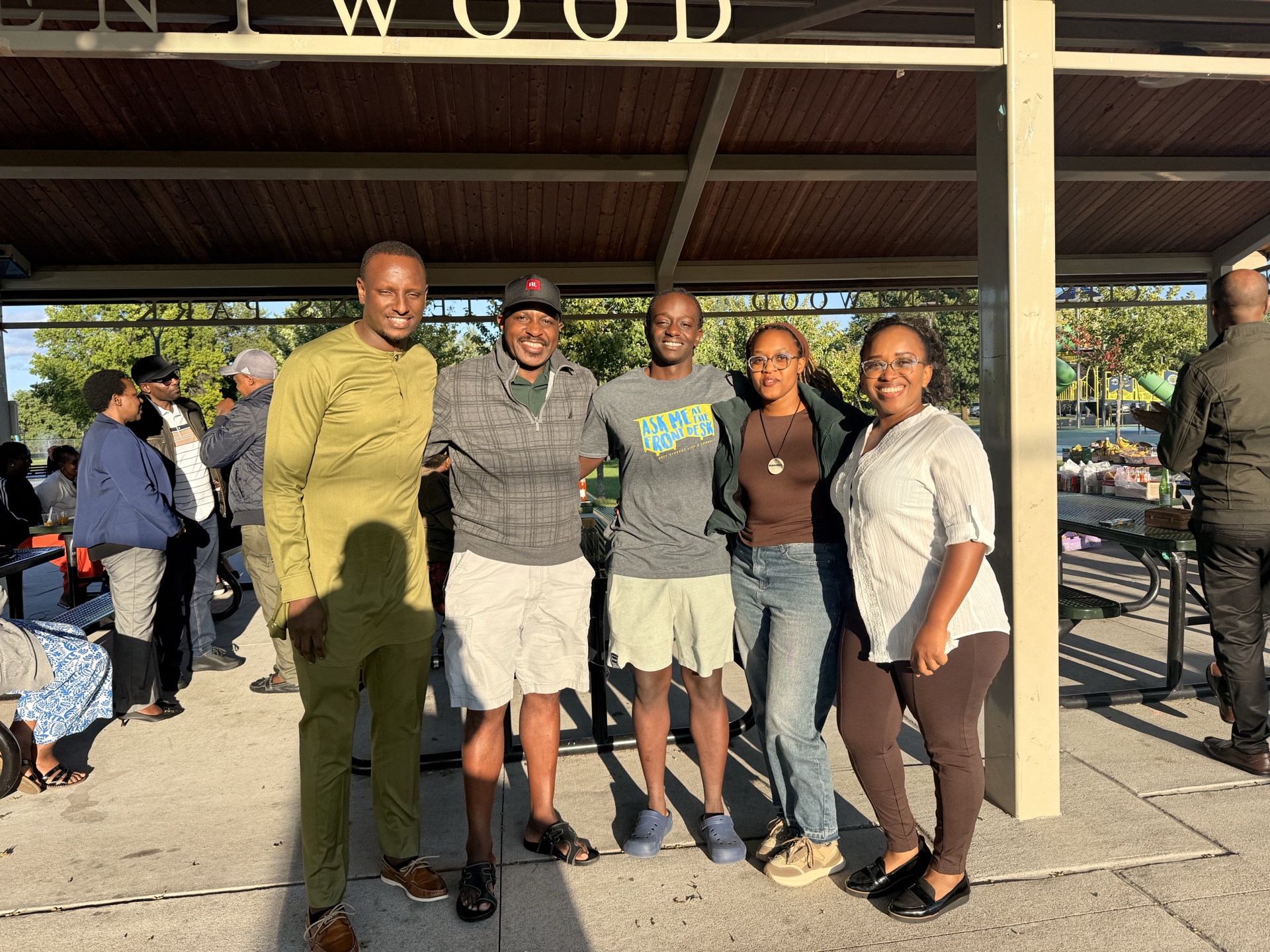 Three community members pose together at the outdoor family gathering.